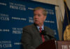 Man in suit speaking at a podium with a microphone