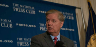 Man in suit speaking at a podium with a microphone