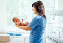 nurse holding newborn in neonatal ward
