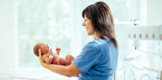 nurse holding newborn in neonatal ward