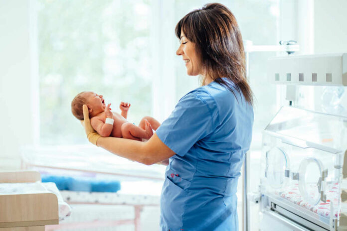 nurse holding newborn in neonatal ward