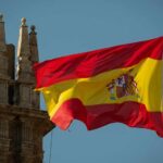 Spain’s Migration Gamble Draws Massive Response Spanish flag waving against a clear blue sky