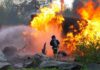 A Historic Treasure Lands In Fire’s Path Firefighter battling a large fire with water spray