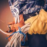 Electrician holding coiled cables with tool belt