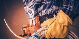 Electrician holding coiled cables with tool belt