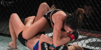 two female mixed martial artists grappling on the mat in a cage