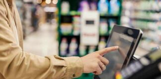 Shopper using self-checkout touchscreen in a grocery store