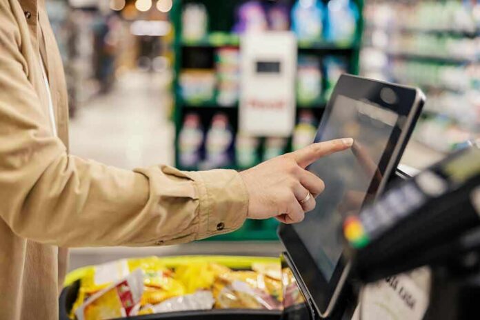 shutterstock_2245009065 Shopper using self-checkout touchscreen in a grocery store