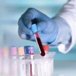 Gloved hand holding a blood sample tube