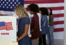 Voters at booths with American flags in a polling place