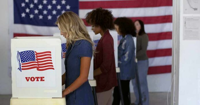Voters at booths with American flags in a polling place