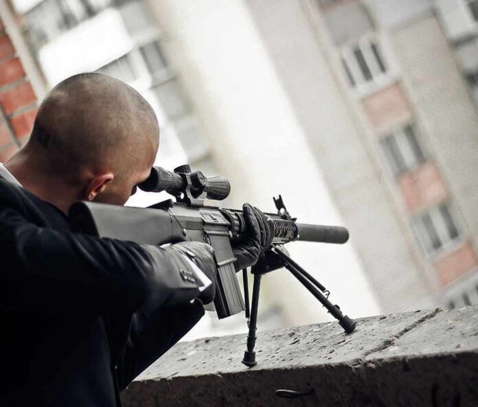 shutterstock_555247681 Person aiming a scoped rifle from a balcony